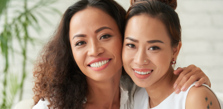 Two smiling women embracing and looking directly at the camera.
